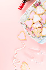 Happy Valentine's day greeting card with heart cookies, wine glasses and wine on pastel pink background.