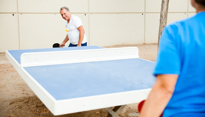 Happy mature man and woman playing table tennis