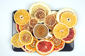 Dried slices of various citrus fruits and black coffee in a white Cup