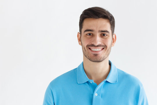 Portrait of smiling handsome man in blue polo shirt, isolated on grey background
