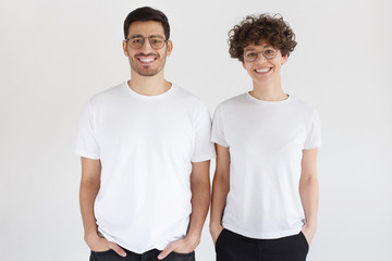 Young smiling couple in blank white t-shirts isolated on gray background