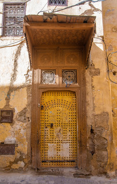 Traditional Moroccan style design of an ancient wooden entry door. In the old Medina. Typical, old, brown intricately carved, studded, Moroccan riad door in Meknes, Morocco.