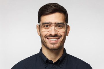 Close-up of young businessman isolated on gray background, smiling with confidence, feeling relaxed and ready for future success