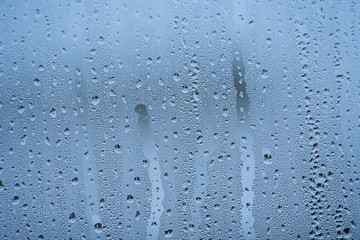 steamy glass. water drops on the glass at home on a blue background