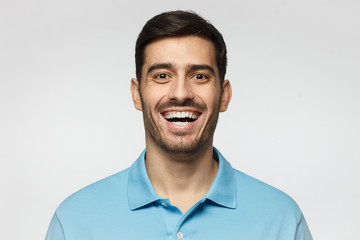 Laughing out loud man. Handsome young man in blue polo shirt smiles broadly, laughing, showing...