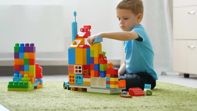 A baby boy plays with colored blocks on a floor