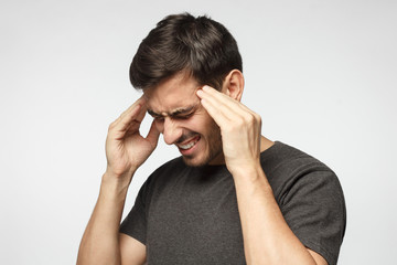 Closeup of young man touching temples with fingers as if suffering from severe migraine, feeling...