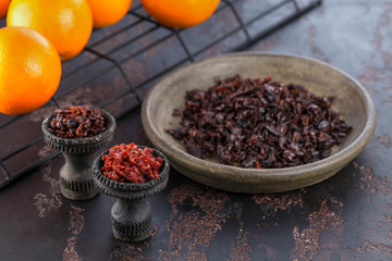 Two black burnt ceramic bowls for hookah Smoking are filled with different types of hookah on the background of ripe oranges and tangerines