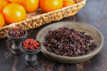 Two black burnt ceramic bowls for hookah Smoking are filled with different types of hookah on the background of ripe oranges and tangerines