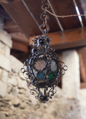 una vecchia lampada in ferro decorata appesa fuori di una casa in montagna - 242002266