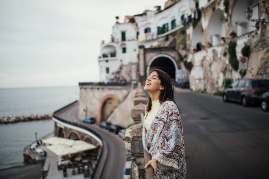 Italian young woman enjoying beautiful sunset in Amalfi on Amalfi coast in southern Italy.Italian experience, day trip to seaside, visiting romantic coastal towns.Vacation destination