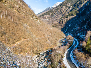 Fototapeta na wymiar Aerial view of mountain road through wild valley in swiss alps in winter