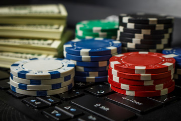 Poker chips and packs of dollars on a laptop keyboard