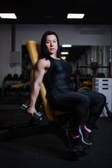 Fototapeta na wymiar fitness girl trains biceps with dumbbells in the gym.