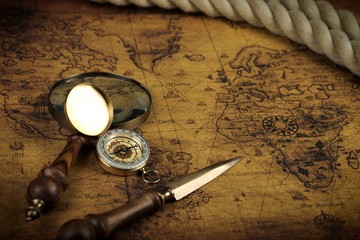 Fototapeta na wymiar Vintage Compass and magnifying glass lies on an ancient world map - adventure stories background