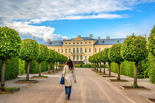 A lonely woman walking near a palace in Latvia, amazing trees and blue sky day