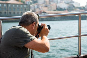 A man from a boat taking pictures of the cityscape of Porto. Selective focus.