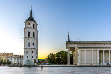 Obraz premium Vilnius, Lithuania - June 20th 2018 - Tourists and locals enjoying a late sunset at Vilnius downtown with a huge church and colorful sky in Lithuania