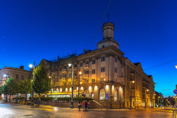 Naklejka premium Vilnius, Lithuania - June 20th 2018 - Tourists and locals walking near a historical building in a early night in Vilnius