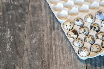 Quail eggs in a paper cast container in the form of a tray on a wooden vintage background. The concept of diet.