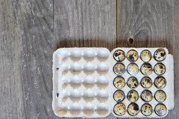 Quail eggs in a paper cast container in the form of a tray on a wooden vintage background. The concept of diet.
