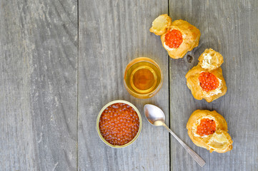 Eclairs with red caviar on wooden rustic vintage background.