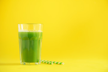 Glass of green celery smoothie on yellow background. Banner with copy space. Fresh juice for detox. Vegan, alkaline healthy diet concept