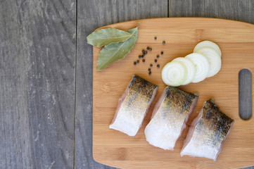 Pieces of fish on a chopping Board with spices on a wooden rustic vintage background. Background, copy space.