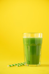 Glass of green celery smoothie on yellow background. Banner with copy space. Fresh juice for detox. Vegan, alkaline healthy diet concept
