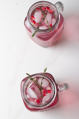 refreshing drink in a glass with pomegranate and thyme with ice and pomegranate slices top view on a white background.