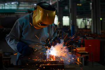 Industrial welder is welding metal part in the factory.