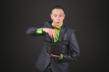 The magician is performing a magic trick with his bowler hat in his hands on a black background.