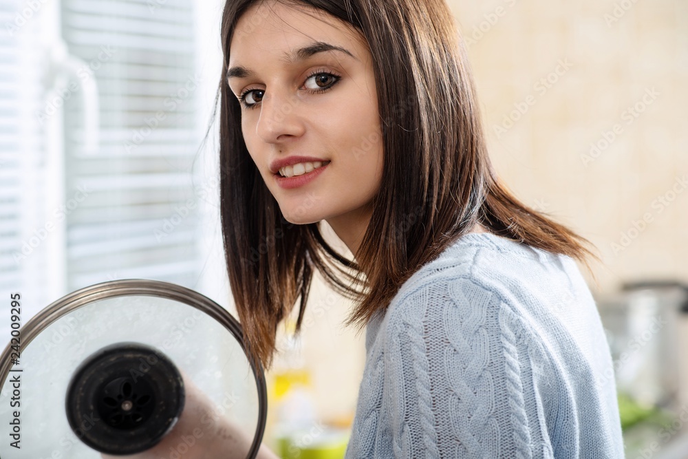 Wall mural pretty young brunette woman cooking in the kitchen