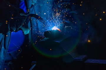 Welder in gloves welds a metal part in the factory.8