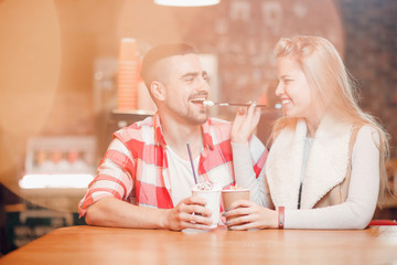 Young beautiful loving couple guy and girl on date in cafe, she sexually gives him lick tube of coffee.