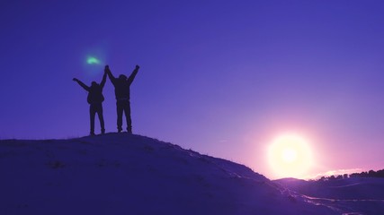 men tourists with backpacks are in winter on hill in rays of bright sun. Climbers on top of snowy mountain rejoice at their successes, raise their hands and happily jump.