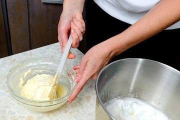 A woman is cooking in her kitchen, about to bake a cake. A woman mixes a mixture of lemon peel, chicken yolks, sugar and flour