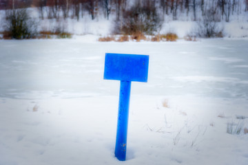 A null blue pointer on the blue iron stick in a forest in winter at shiny and frosty morning. sun shine directly into the camera. At this pointer you can place your text.