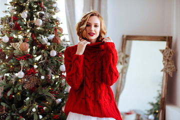 holidays, celebration and people concept - smiling woman in red sweater over christmas tree background