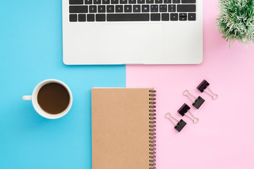Creative flat lay photo of workspace desk. Top view office desk with laptop, clip, notebook, coffee cup and plant on blue pink color background. Top view with copy space, flat lay photography.