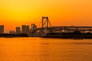 Tokyo skyline and rainbow bridge at sunset in Odaiba waterfront.