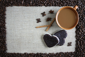 Filiżanka kawy, pierniki i cynamon, woków obramowanie z ziaren kawy