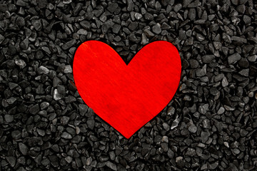 Red painted wooden heart on a grey stones background