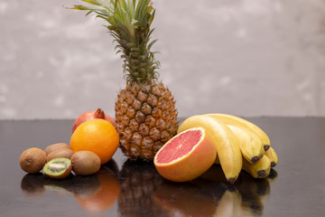 several bananas and kiwi next to exotic fruits, chalk background