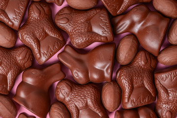 delicious chocolate Easter eggs, bunnies and lambs over pink pattern background