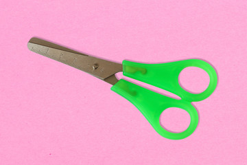 Scissors on pink background close up