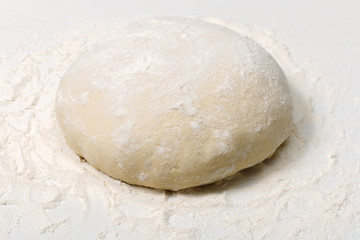 Fototapeta na wymiar Raw fresh dough in flour on a white background
