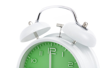 Cropped twin bells analogue alarm clock with green clock face shows completed hour, concept on...