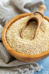 Raw quinoa and a scoop in a wooden bowl.