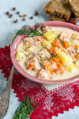 Creamy soup with salmon, vegetables and fresh dill in a bowl.